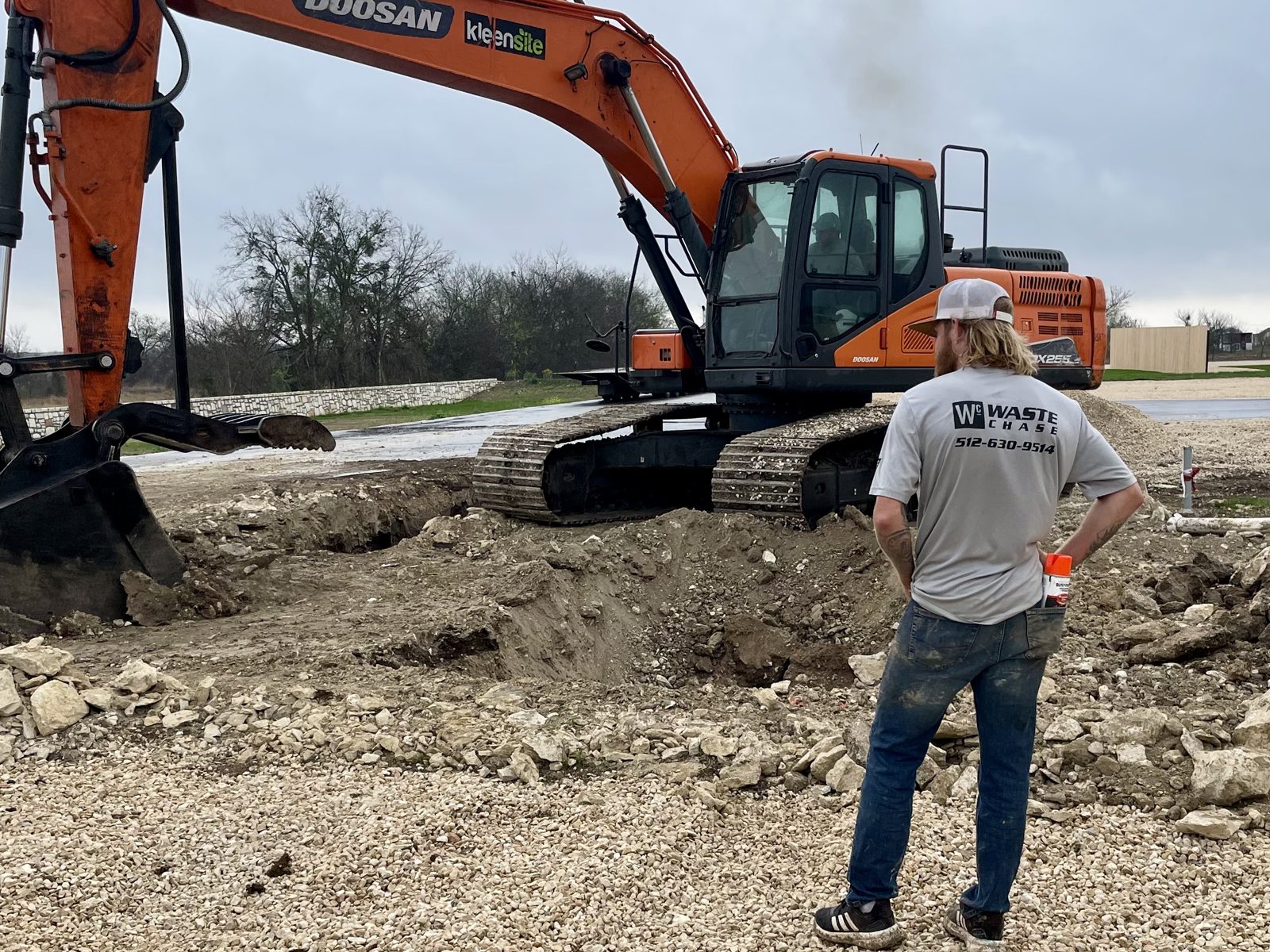Waste Chase crew member watching an excavator dig on a septic job