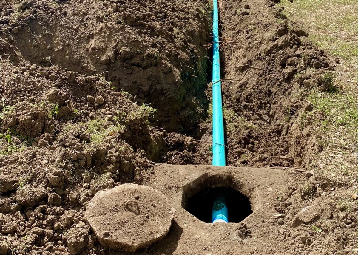 Septic outlet line exposed in a trench beside an open tank lid