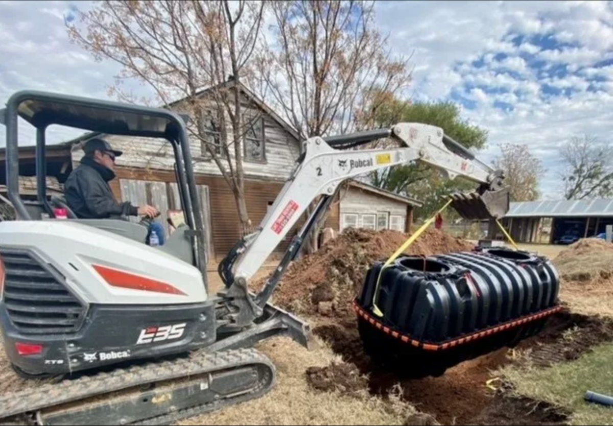 New septic tank being set into an excavated hole